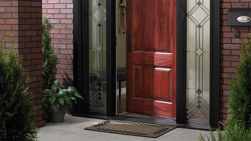 A modern reddish brown fibreglass front entry doors with black trim and custom sidelites.