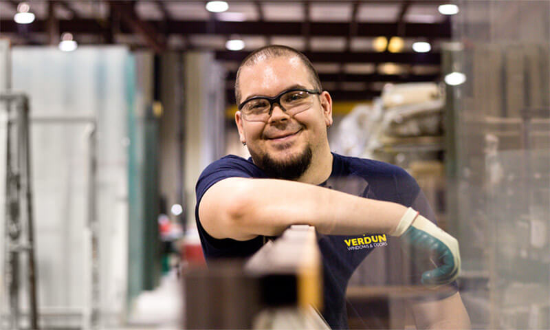 A window manufacturer poses for a picture leaning on a vinyl replacement window.